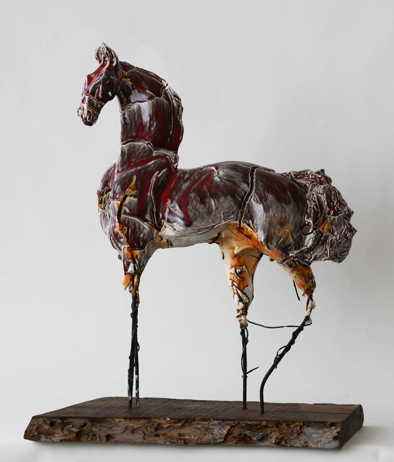Glazed ceramic horse sculpture in deep red on a driftwood base by Carl Dahl.