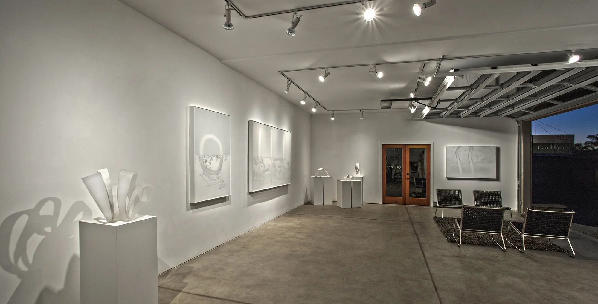 Inside Susan Street Fine Art at dusk — sculptures and paintings under gallery lighting.