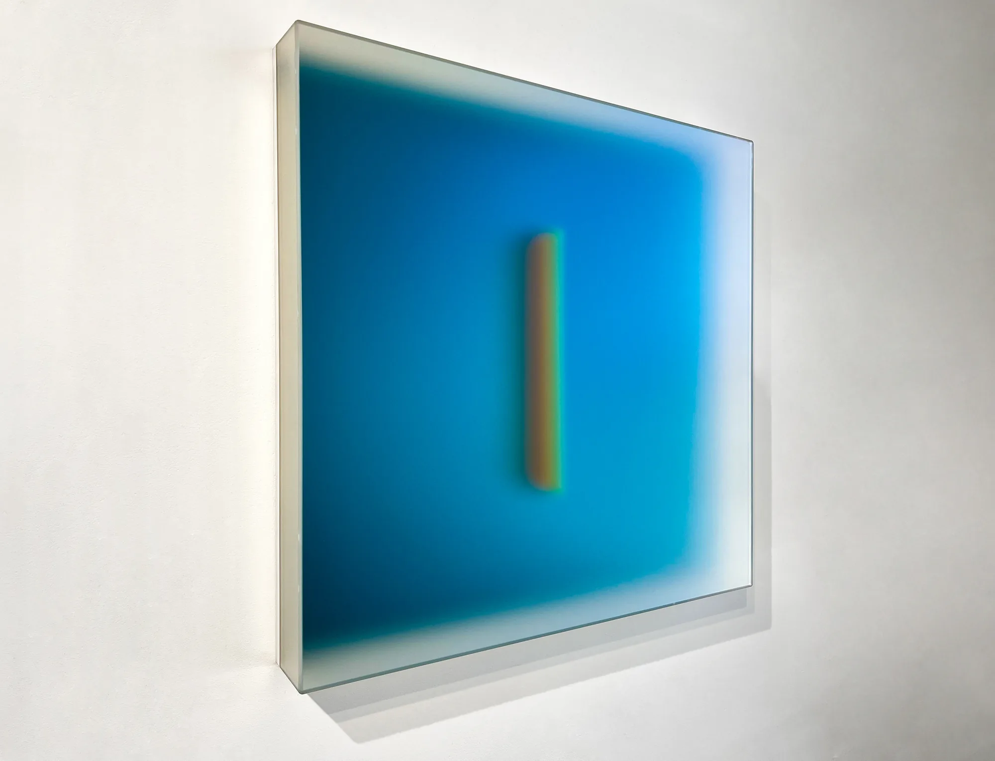 A luminous teal glass light panel, Teal Glyph, by Casper Brindle on a white gallery wall.